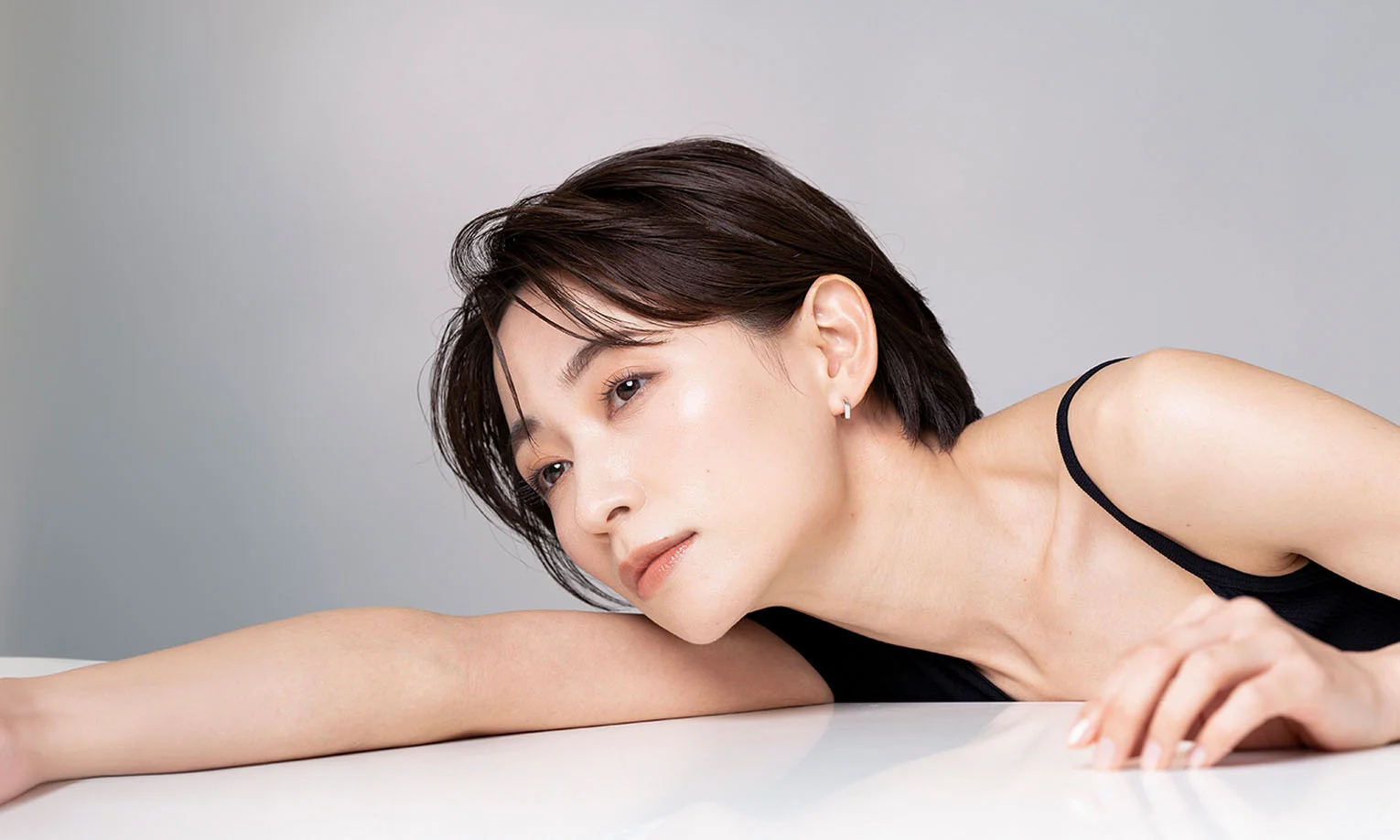 A close-up of a woman with short hair lying gracefully on a reflective surface, exuding serenity - Arm Lift in West Hollywood, CA