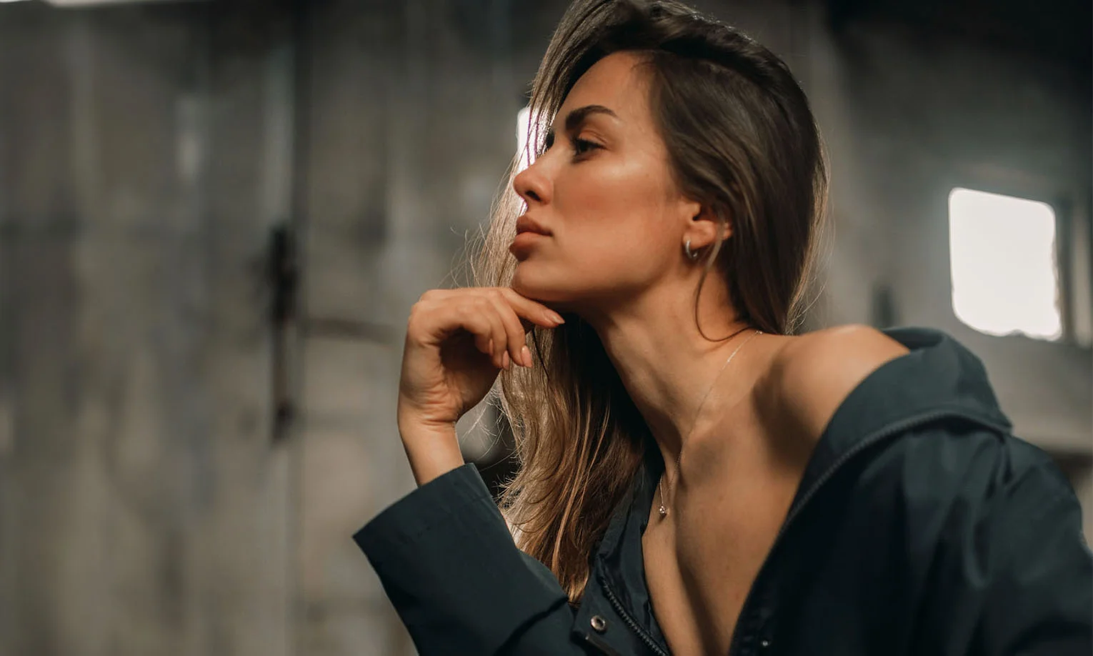 A woman in a casual outfit leaning her chin on her hand, with a thoughtful expression, set in an industrial-style interior - Profile Balancing in West Hollywood, CA